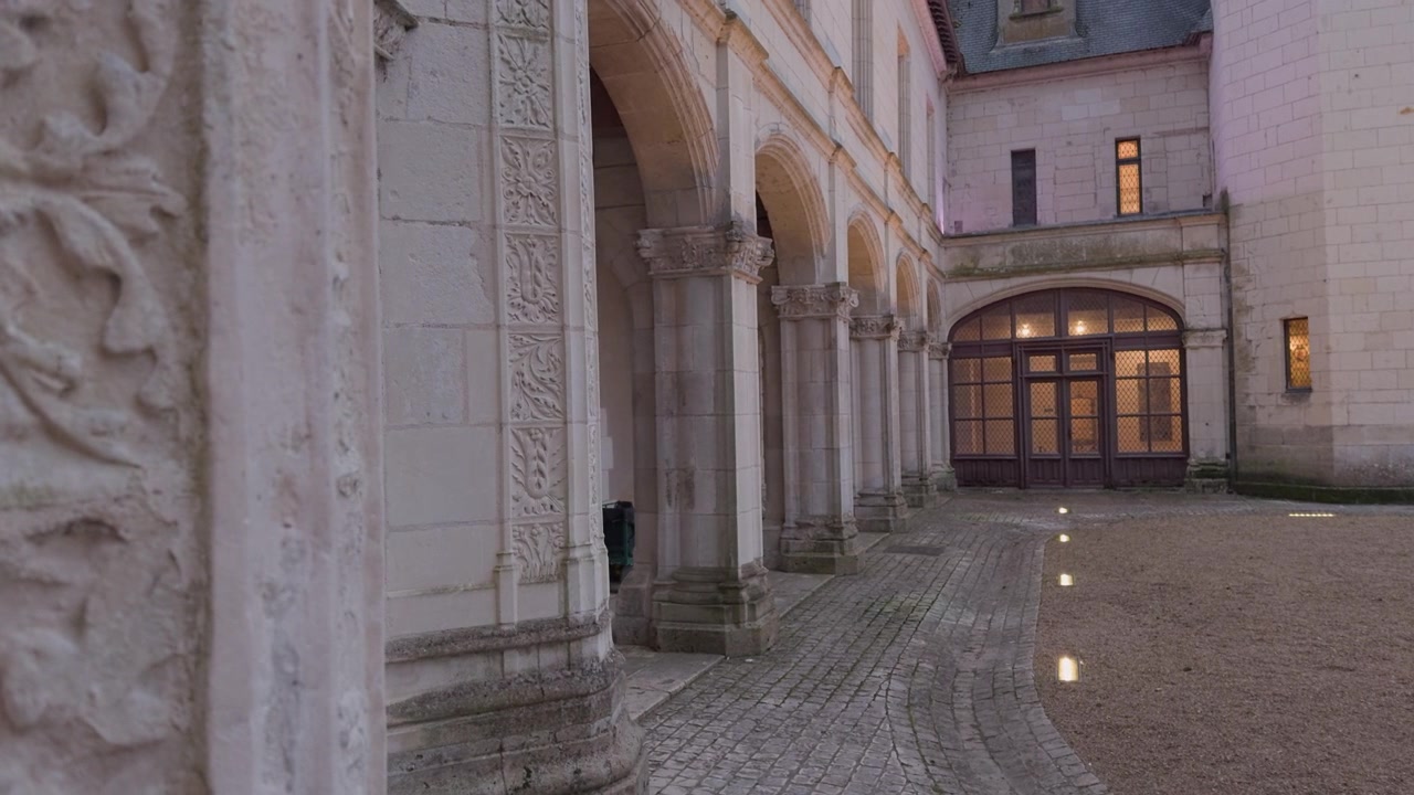 Eleganti archi in pietra nel cortile di Chaumont-sur-Loire al crepuscolo, con accenti di luce calda.