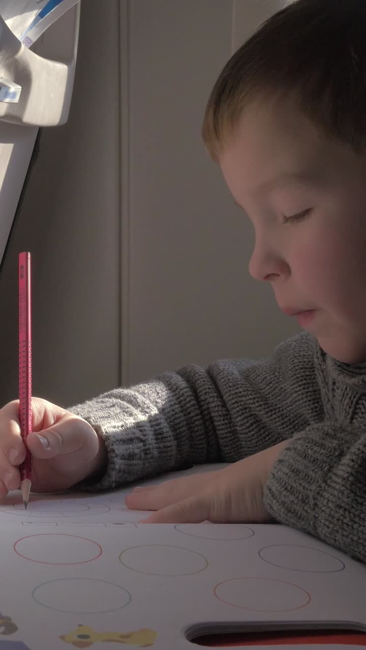 Ragazzo che disegna e colora su un quaderno con una matita