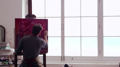 male artist works on painting in daylight studio shot on r3d