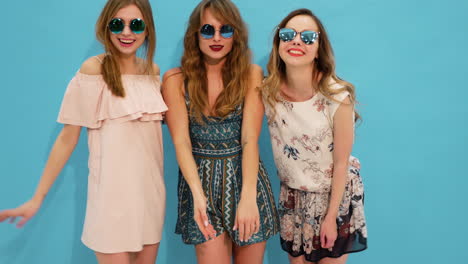 three beautiful women in summer dresses and sunglasses