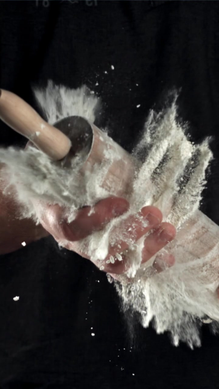 Slowmotion af mel, der eksploderer fra en kagerulle ned på en hånd