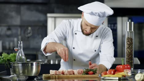 chef masculino salando carne en cámara lenta en la cocina. hombre profesional cocinando plato