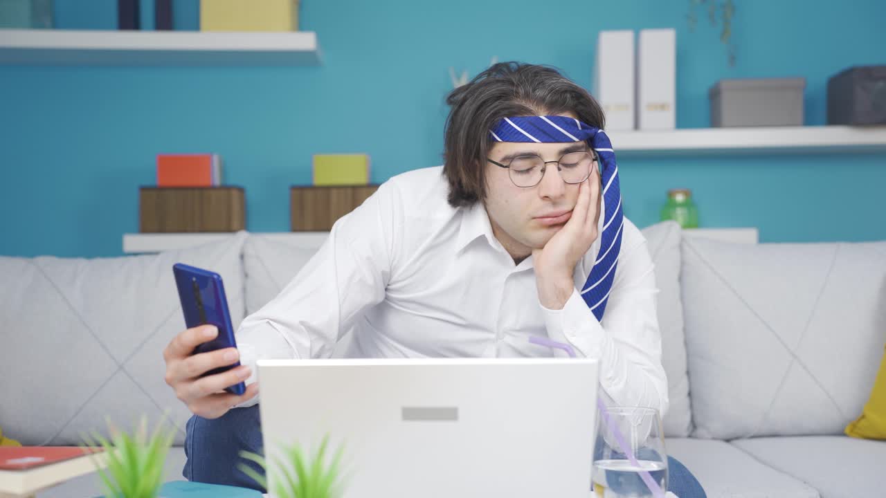 지루한 홈 오피스 직원이 집에서 전화를 보고 있습니다.