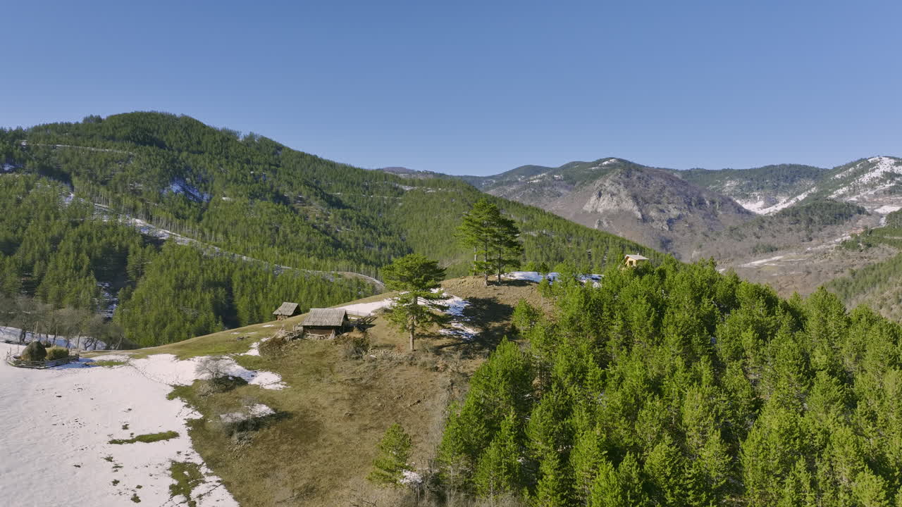 Vista aerea di un paesaggio montano invernale con foreste sempreverdi e piccole baite in legno