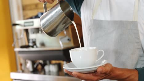camarero masculino vertiendo leche en la taza 4k