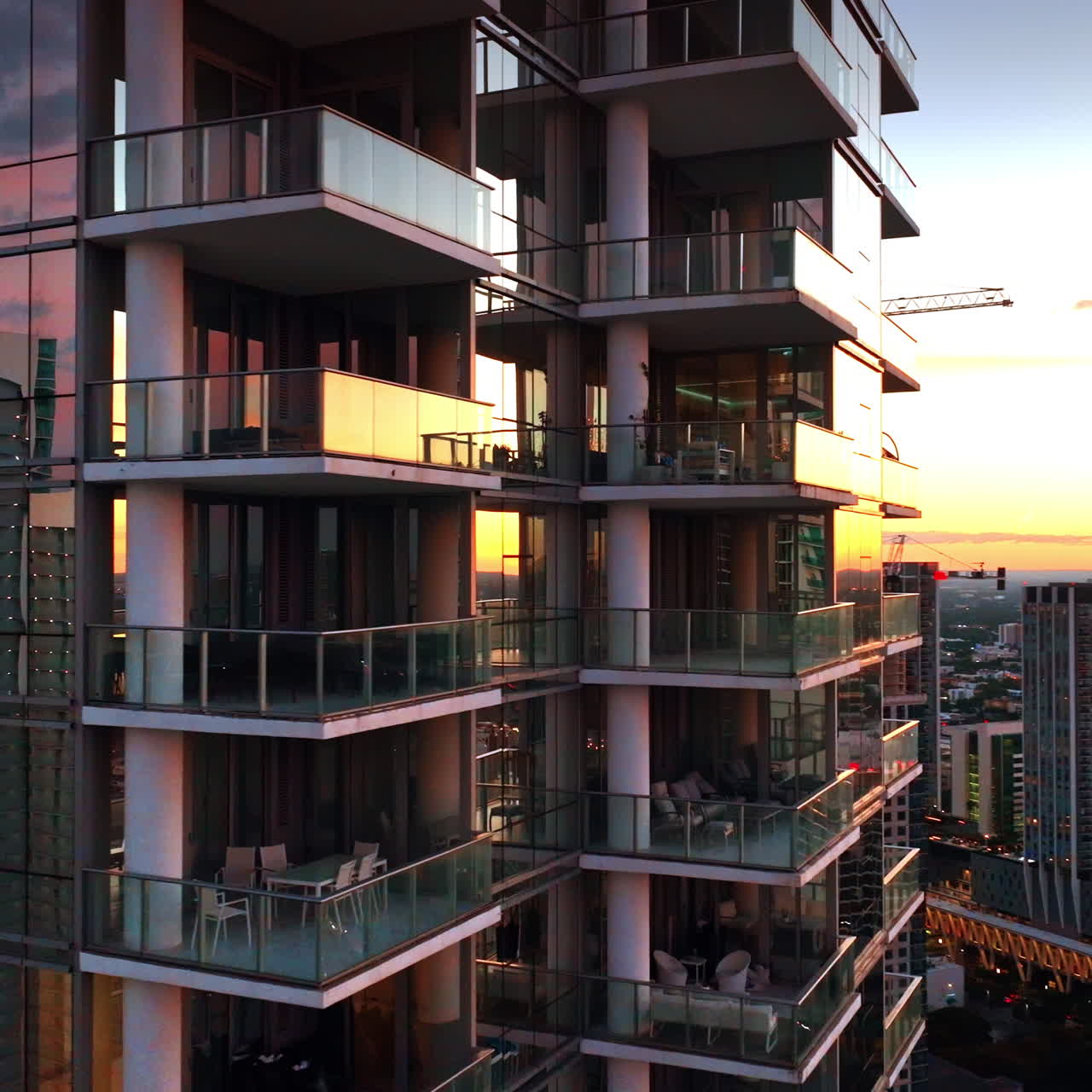 Flying around the luxurious modern high-rise building with windows reflecting light at sunset. Block of flats in Miami, Florida, USA.