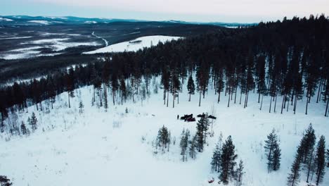 disparo de drone de un grupo de personas paradas en la cima de una montaña con motos de nieve durante la puesta de sol desde la distancia con una hermosa vista