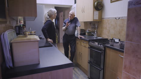 an elderly couple conversing in their kitchen