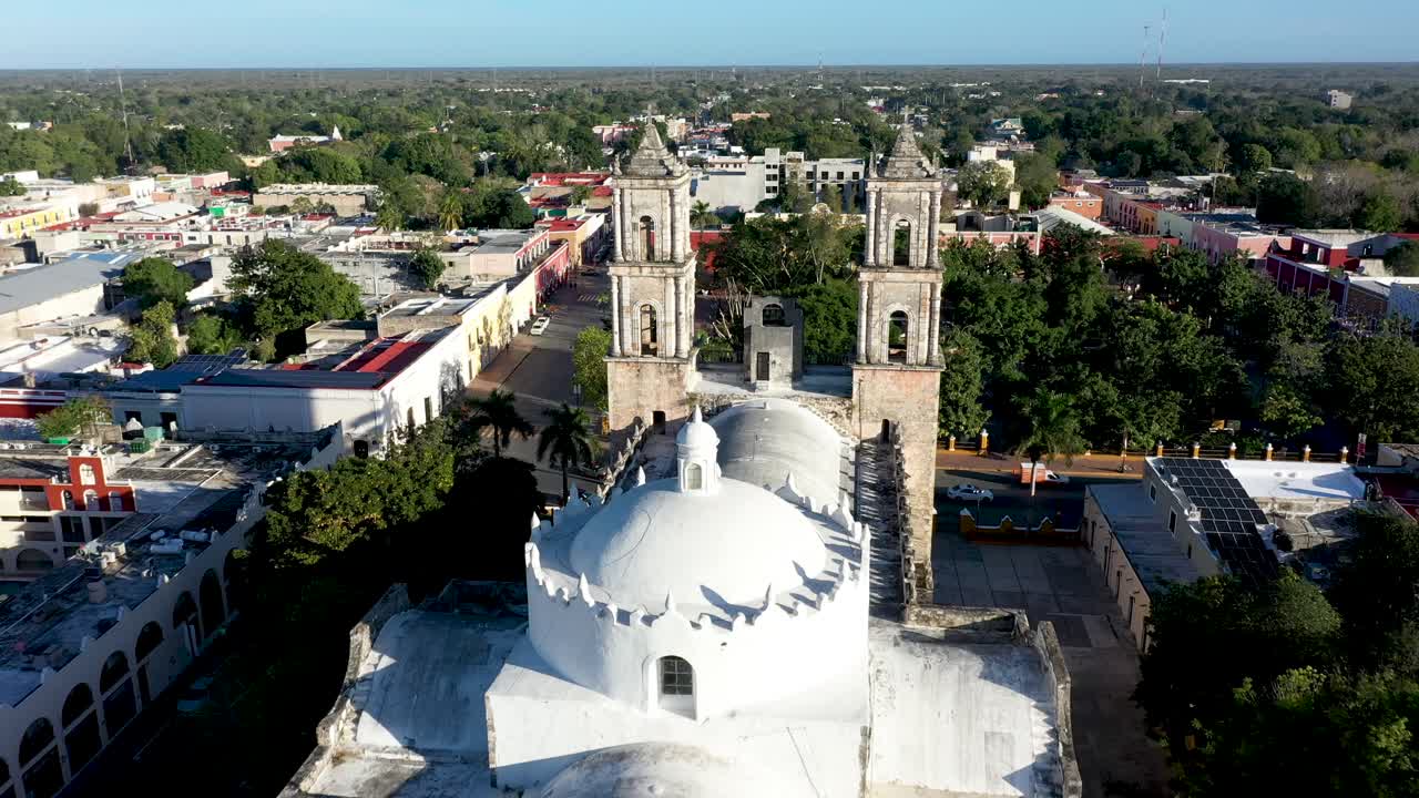 Aerial push in to the towers from back of the Catedral de San Gervasio showing full depth of the church in Valladolid, Yucatan, Mexico just after sunrise