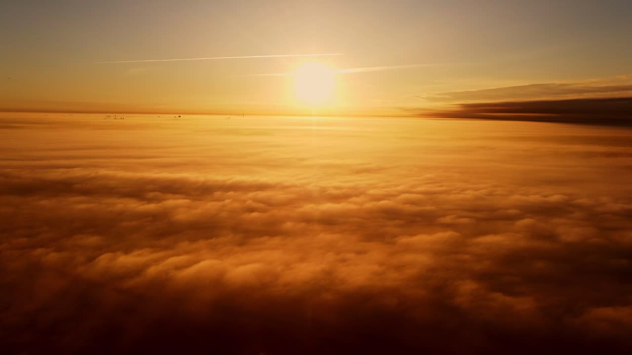 Sun rises above endless clouds in warm amber hues, creating a tranquil horizon