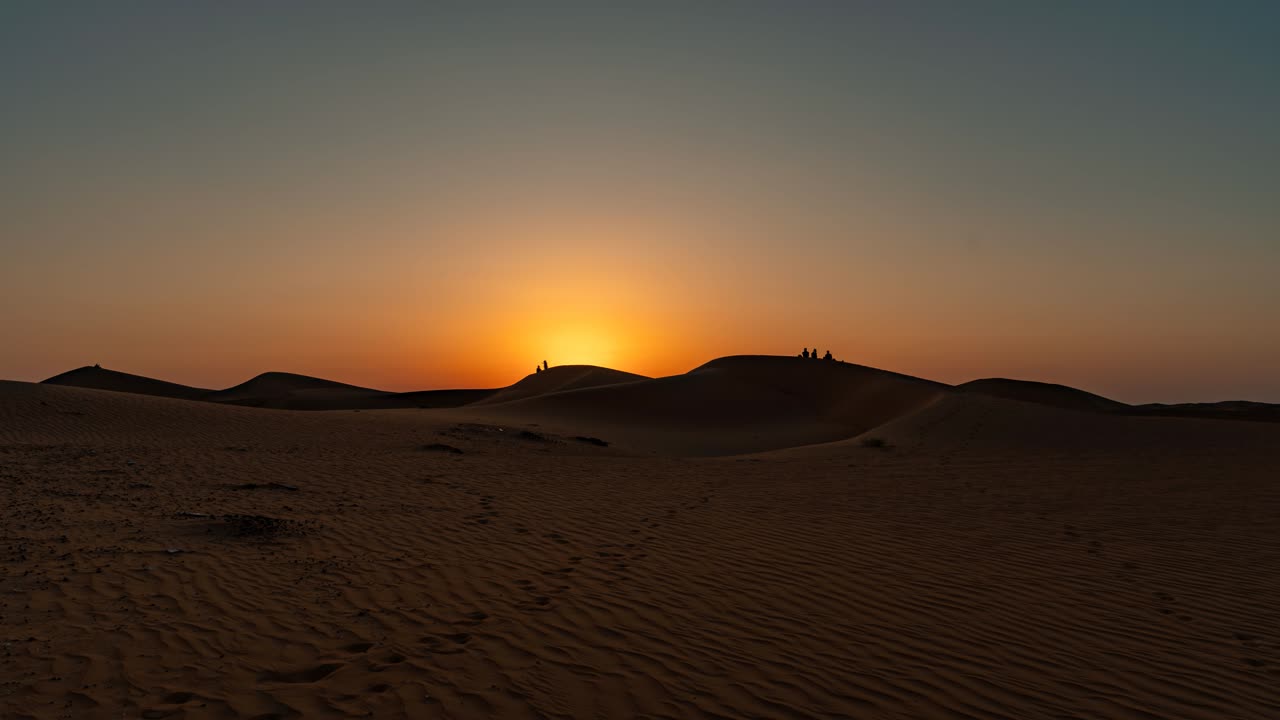 puesta de sol sobre las dunas del desierto con personas en un picnic en silueta - lapso de tiempo