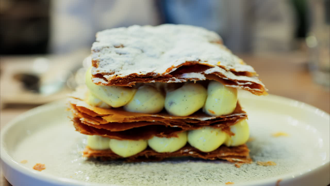 Primo piano di un Millefoglie al pistacchio su un piatto verde in un ristorante