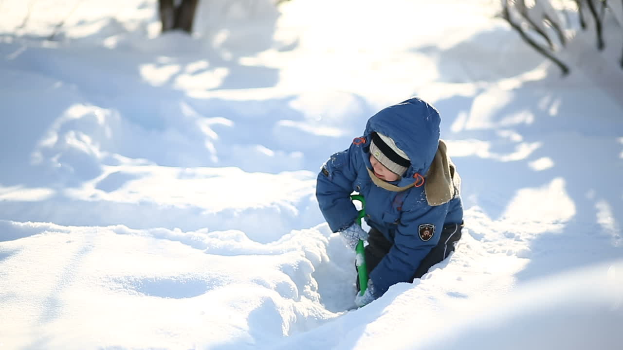 Boy playing in winter. Little boy walking outdoor in the winter time and playing with snow