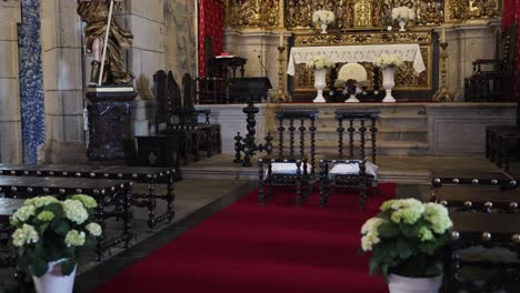 interior of ornately decorated church with floral altar and red carpet set for wedding ceremony