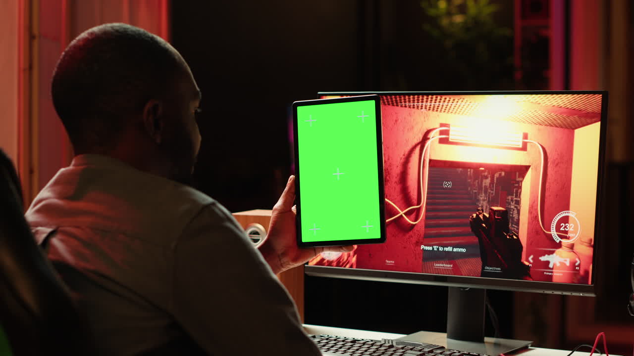 Man watching videos on green screen tablet while playing PC games