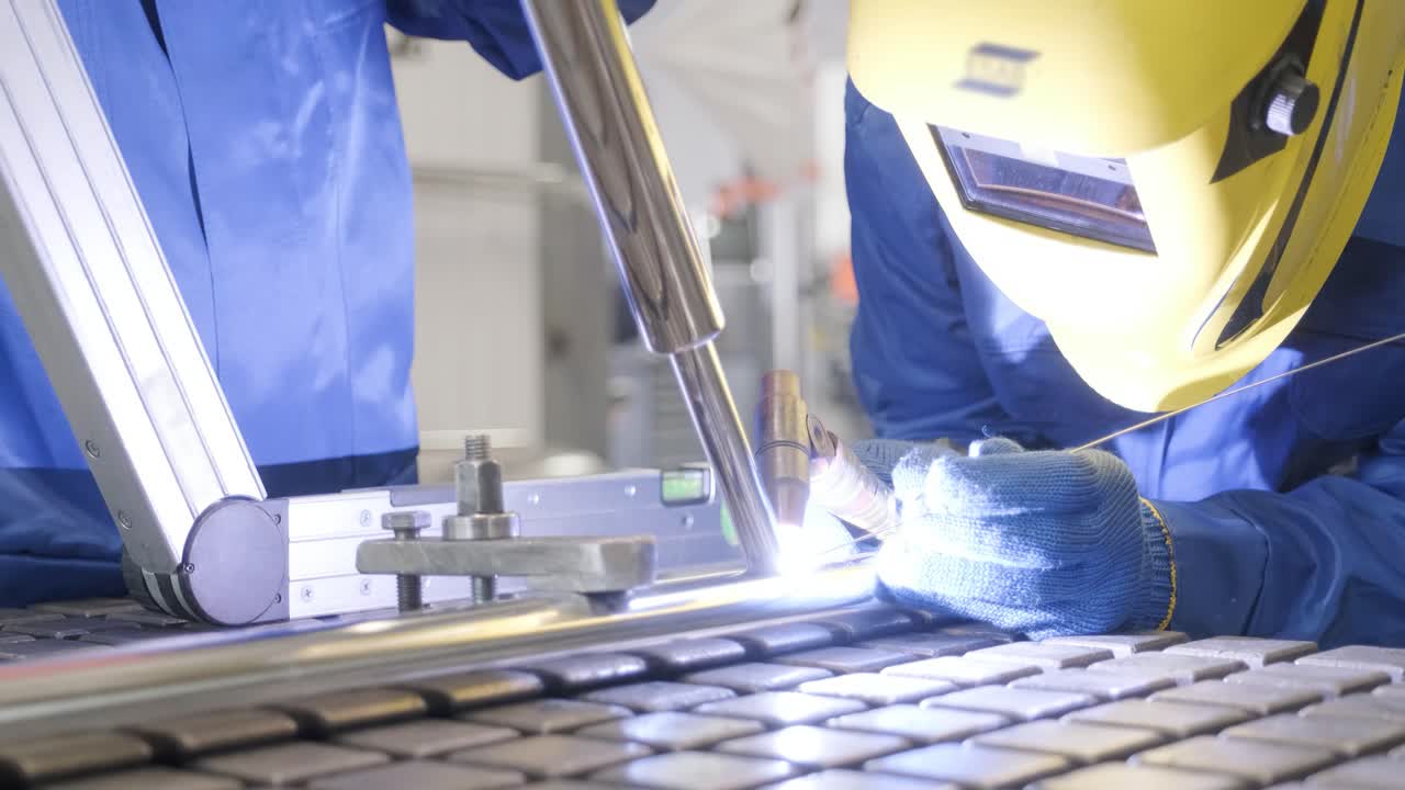 워크에서 마스크를 착용 한 남자의 클로즈업 금속 노동자는 수동 노동을 사용합니다. 숙련 된 용접기. 용접기는 공장에서 스테인리스 스 파이프를 용접합니다.