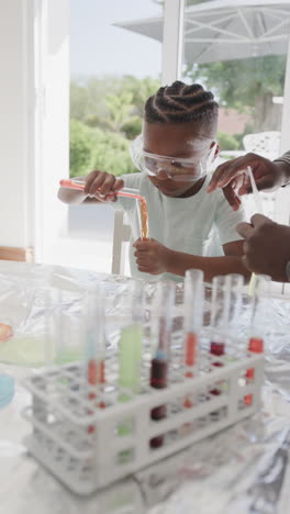 vertical video of african american father and son holding test tubes with liquid, slow motion
