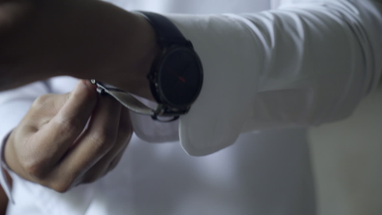 Close up of man in dress shirt putting on watch