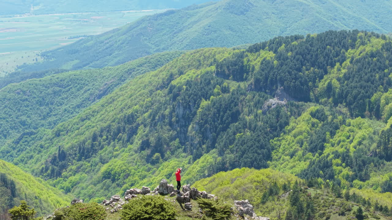 A solo trekker walks along a narrow trail lined with blooming greenery and fresh spring colors in the hills of Bulgaria. A tranquil journey into nature and self-discovery.