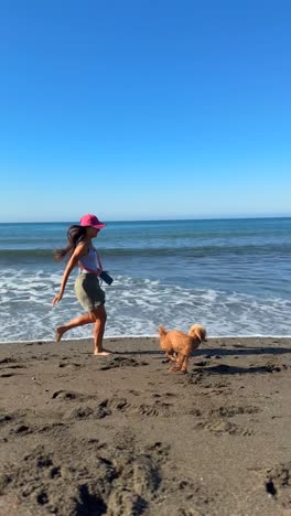mujer jugando con su perro en la playa