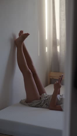 Woman relaxing in bed with legs up