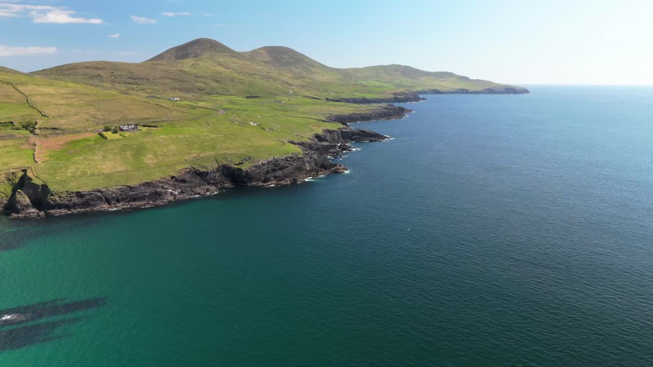 Drone flight along the Irish coastline reveals rugged cliffs, rolling green hills, and endless blue ocean. Majestic and untamed coastal beauty.