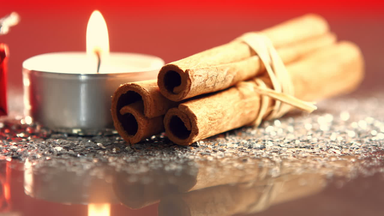View of candle burning next to cinnamon