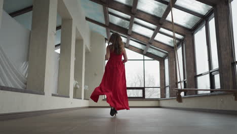 woman dashes toward window in gallery. rose in woman hand adds burst of color to movement of scarlet dress in art gallery. symbol of dynamic beauty