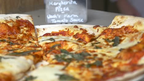 slow motion tilt down on fresh baked thin crust margherita pizza with chefs in background