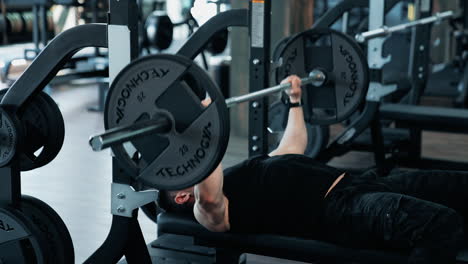 bodybuilder doing barbell exercise. young man flexing muscles with barbell in the gym