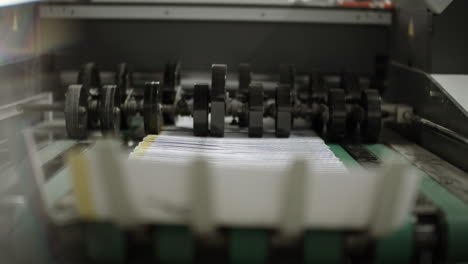 close up of a printing machine, peper traveling on the production line and stopping on the curved end of the machine