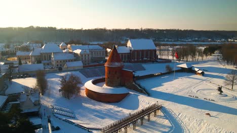 Drone-shot-of-the-historic-old-red-brick-Kaunas-Castle-in-Kaunas-old-town,-Lithuania-during-cold-snowy-winter