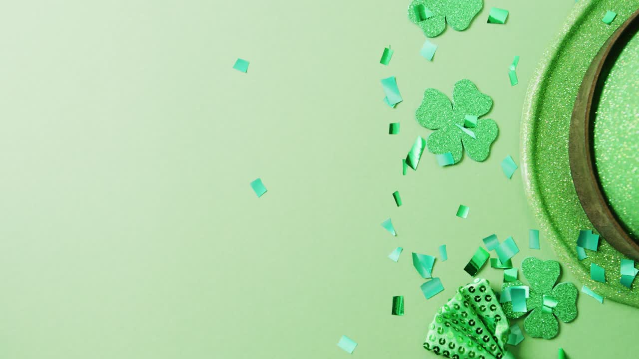 Video of st patrick's green shamrock leaves and hat with copy space on green background