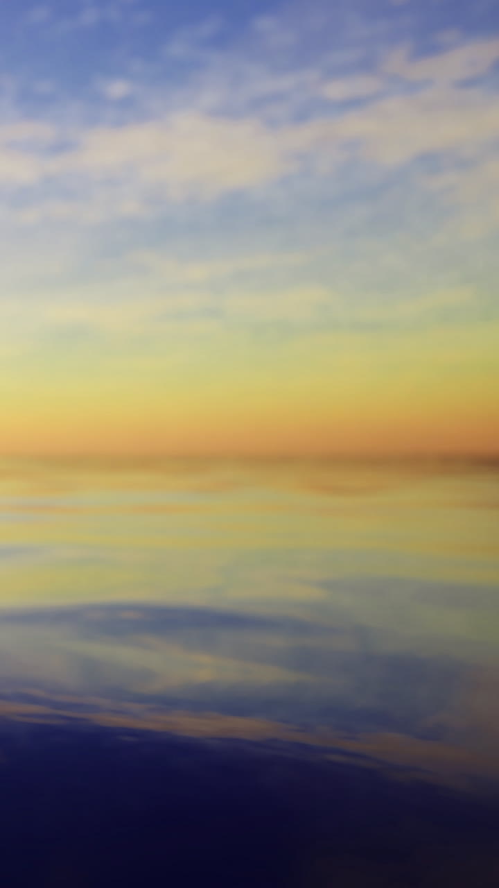 Sunset over calm water with soft clouds in the sky at dusk
