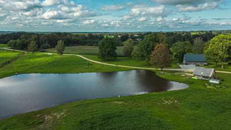 aerial orbital hyperlapse over scenic landscape of latvia with views over a lake and farmhouse