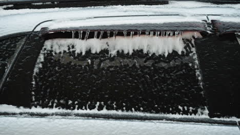 primer plano de un coche cubierto de nieve y hielo en invierno, mostrando las fuertes nevadas y patrones de heladas en el vehículo y la ventana