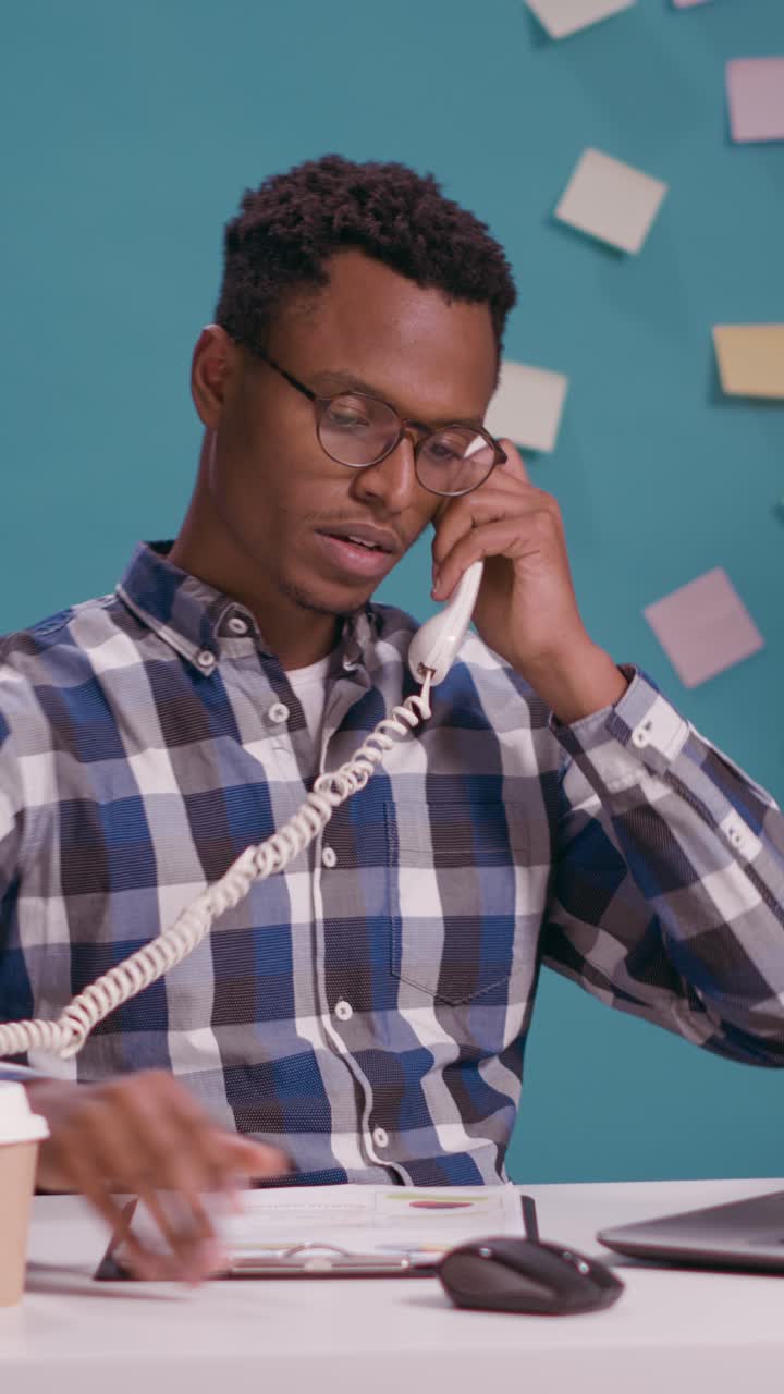 Man working at desk with computer and talking on phone