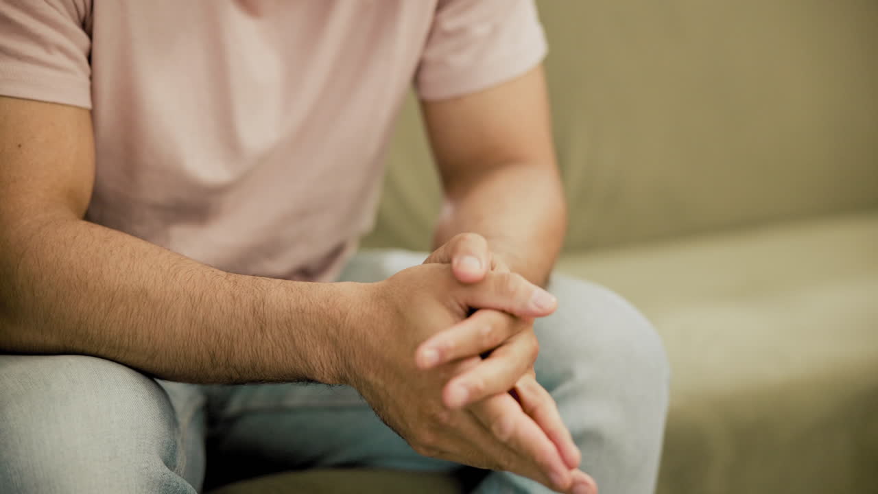 hombre sentado en un sofá, gestando con las manos