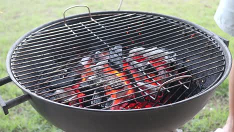 arranging burning charcoal on a charcoal bbq