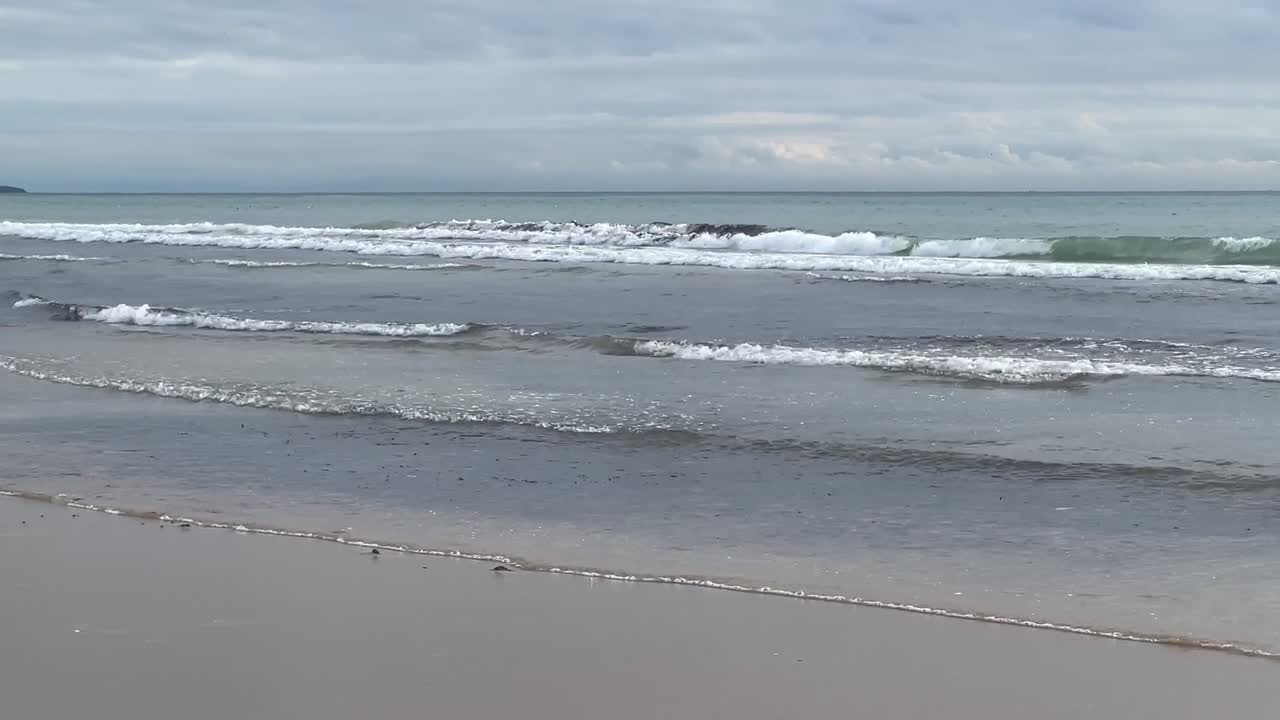 바다의 물결이 스스로 형성되고 모래 해변에 어지는 느린 동작으로 기록된 자연스러운 바다 해안 환경 개념
