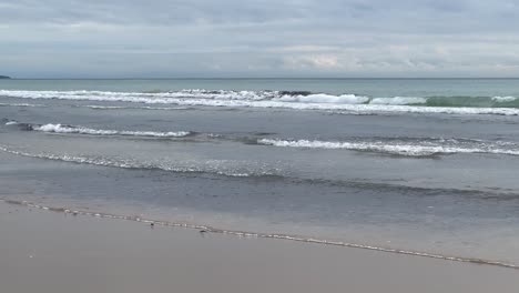 las olas del mar se están formando y salpicando en la playa de arena, grabado en cámara lenta, concepto de entorno natural de la costa del océano