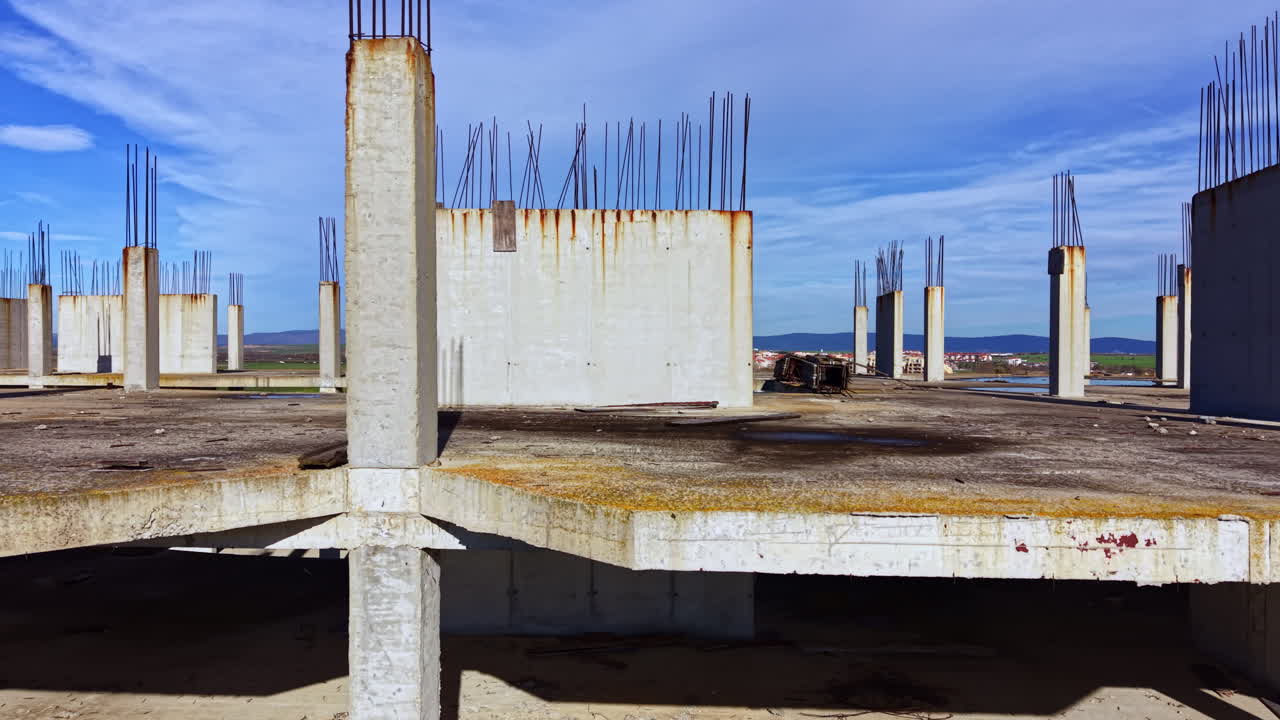 Construction of a new building unfolds under the wide sky beside a tranquil body of water on a bright day