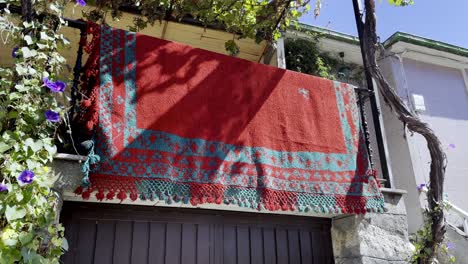 Red-ornate-shawl-cloth-hangs-off-balcony-from-house-in-lonoa-spain