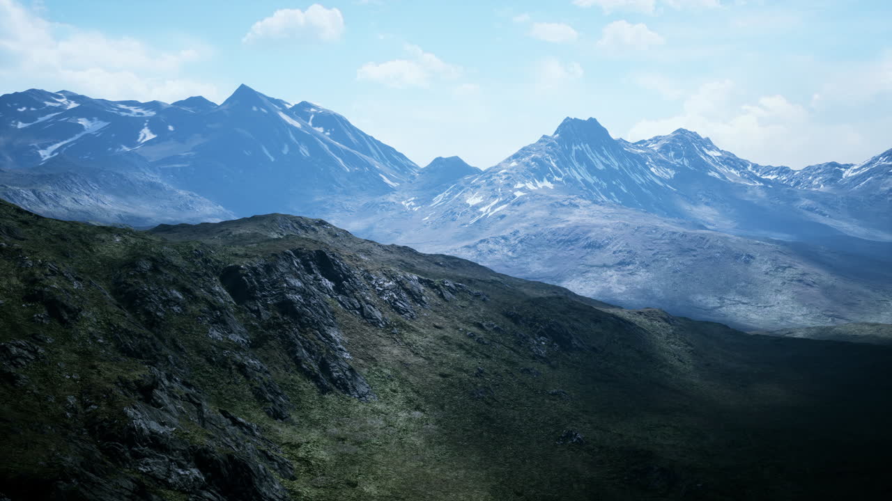 Luftaufnahme über einem Tal mit schneebedeckten Bergen in der Ferne