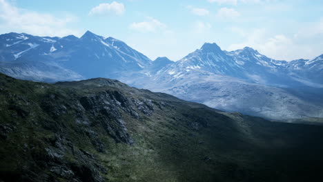 Aerial-Over-Valley-With-Snow-Capped-Mountains-In-Distance