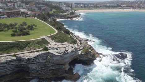 waves crashing against rocky cliffs of mackenzies point peninsula - tourists at marks park and coastal walk - sydney, nsw, australia