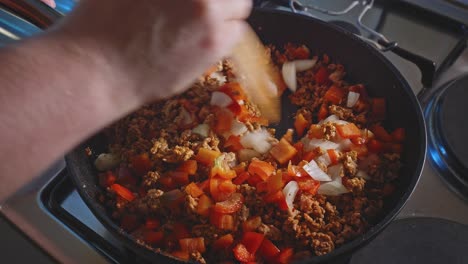 stirring chopped red bell pepper, white onion, and ground turkey in a cooking pan