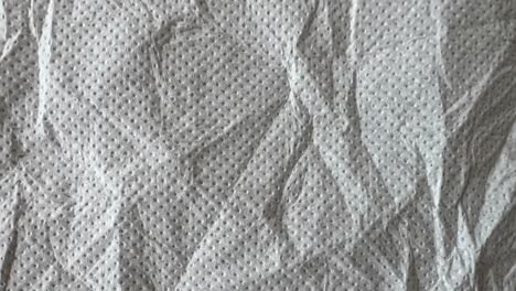 close-up view of a crumpled piece of gray nonwoven fabric showcasing tiny holes throughout its surface, creating an interesting textured background ideal for various design purposes