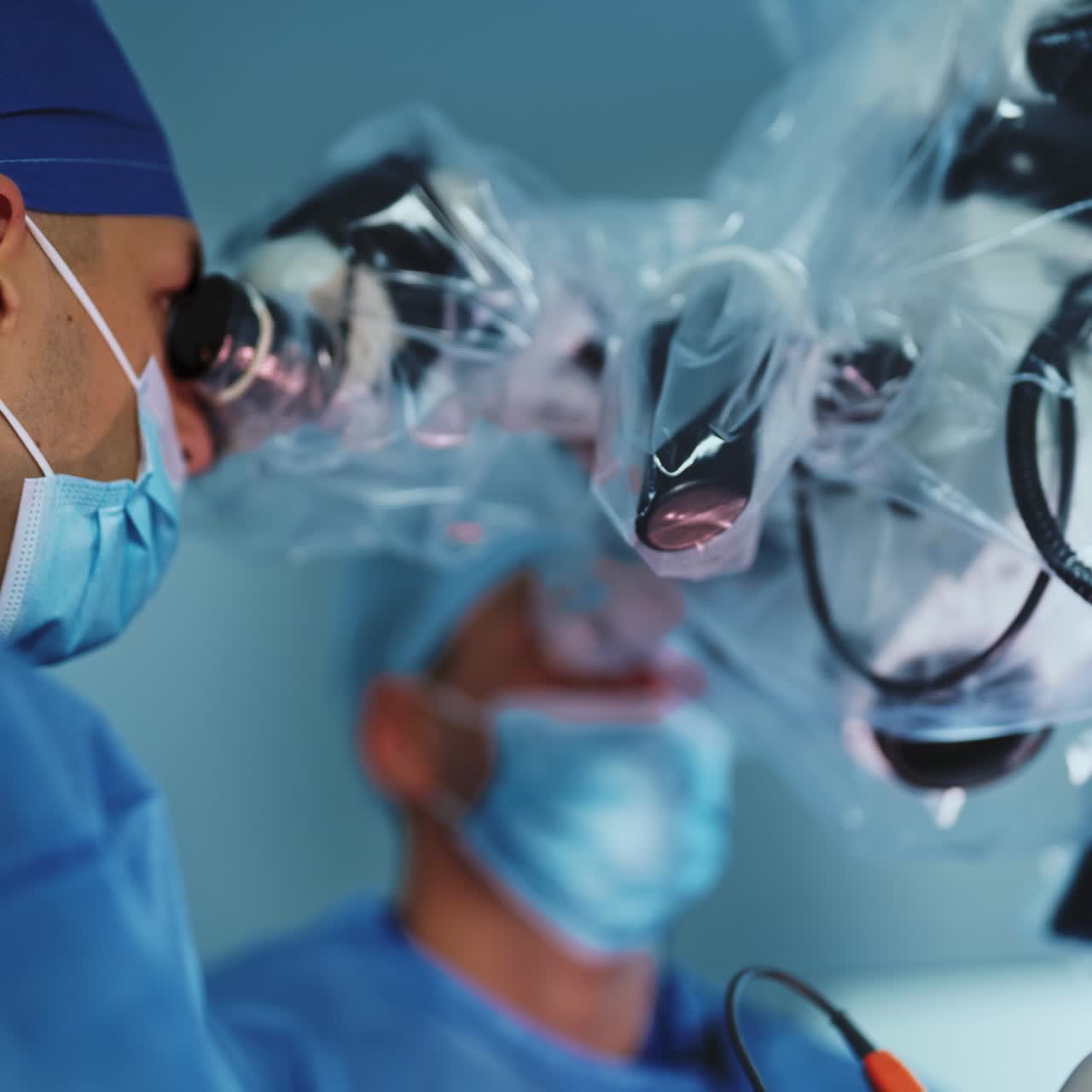 Skilled surgeons operating the patient. Doctors work, look at microscope and discuss the process. Close up. Low angle view