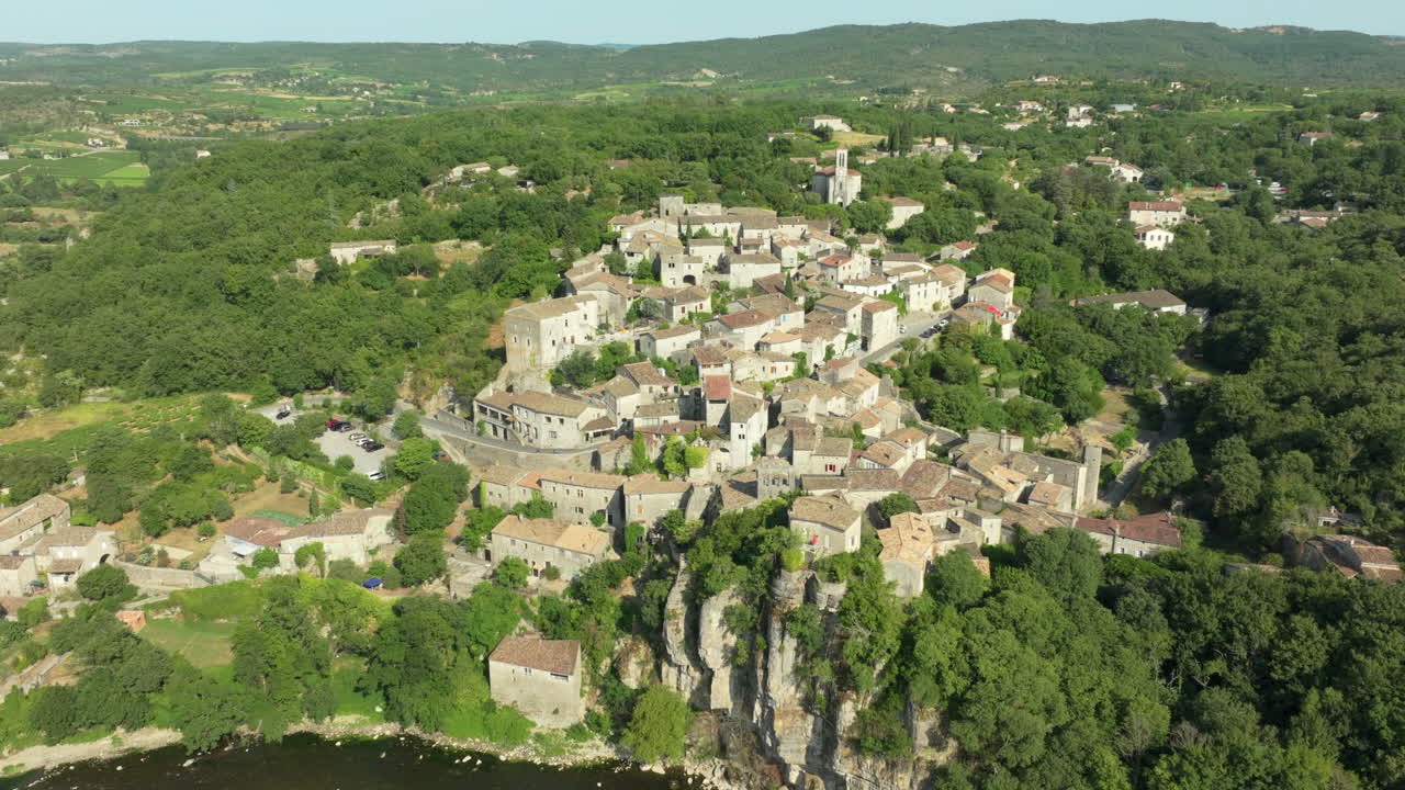 Plan aérien en recul du village de Balazuc et de la rivière Ardèche révélant le paysage.